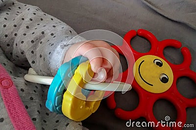 Hand of baby laying on back, holding toy Stock Photo