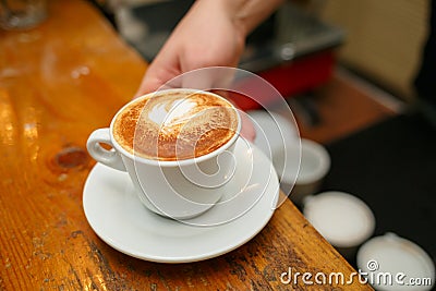 Hand barista holding and serving cup of coffee. Stock Photo