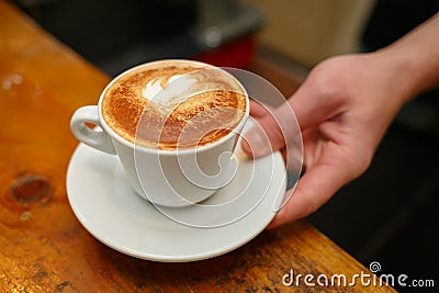 Hand barista holding and serving cup of coffee. Stock Photo