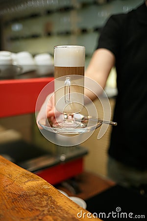 Hand barista holding and serving glass of latte Stock Photo