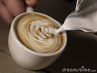 Hand of barista making cappuccino coffee pouring milk making lat Stock Photo