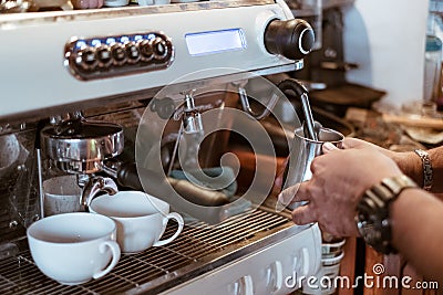 Hand barista steam milk in metal mug on coffee maker Stock Photo