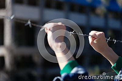 Hand behind barbed wire in prison or slavery closeup Stock Photo