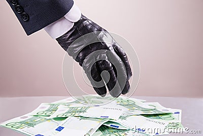 Hand in black glove steals money, bribe and corruption concept Stock Photo