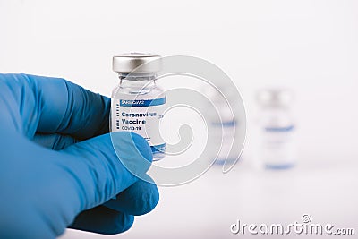 Hand with blue latex glove holding covid vaccine vial Stock Photo