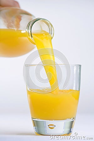 Hand, Bottle pouring Orange juice over glass Stock Photo