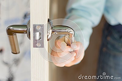 The hand of the boy holding the door handle opening it Stock Photo