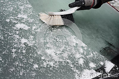 Hand broom sweeps the snow from the windshield of a car in winter, copy space Stock Photo