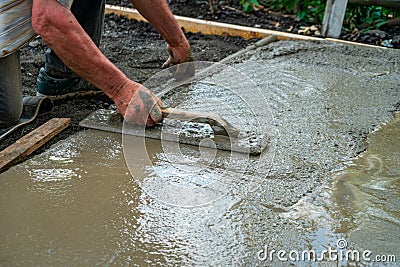 Hand builder with trowel leveling concrete, spreading poured Stock Photo