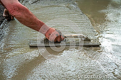 Hand builder with trowel leveling concrete, spreading poured Stock Photo