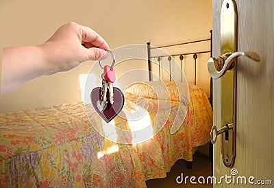 hand with bunch keys against old-fashioned room on sunny day, iron bed filled with bedspread, bright light from window, Room for Stock Photo