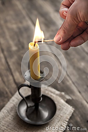 Hand burning candle on wooden background Stock Photo