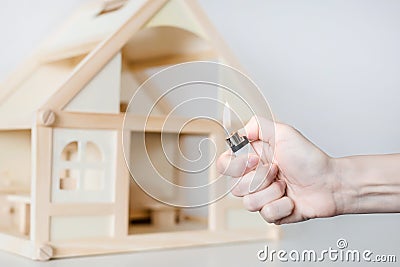 Hand with burning lighter against wooden house model on the background. Arson of house concept. Criminal accident Stock Photo