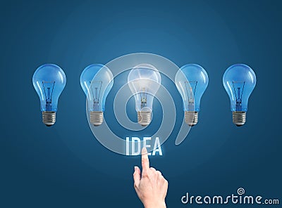 Hand of the businessman clicks on the button the idea and lit the lamp. Stock Photo