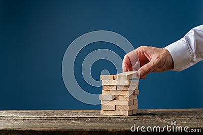 Hand of a businessman making a stack of wooden pegs Stock Photo