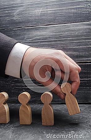 The hand of a businessman puts a wooden figure of a man in a row to other employees. The concept of business management Stock Photo