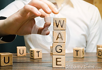 Hand of a businessman removes wooden blocks with the word Wage. Salary reduction concept. Wages cuts. The concept of limited Stock Photo