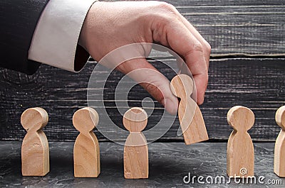 hand of a businessman takes a wooden figure of a man. The concept of search, hiring and firing workers, promotion. Stock Photo