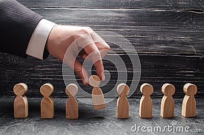 hand of a businessman takes a wooden figure of a man. Stock Photo