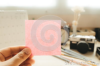 Hand of businesswoman holding post it note with camera and calendar placed background. image for workplace, note, blank concept Stock Photo