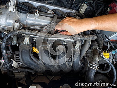 Hand of car mechanic working in auto repair service. He have fix old car engine streaked with dust and oil stains Stock Photo