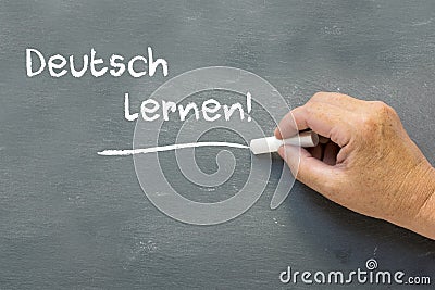 Hand on a chalkboard with the German words Deutsch lernen (Learn Stock Photo