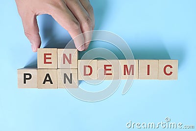 Hand changing word pandemic to endemic in wooden blocks. Covid-19 transition from pandemic to endemic concept. Stock Photo