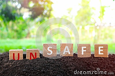 Hand changing word unsafe to safe in wooden blocks on natural background. Safety on workplace and precautionary safe acts. Stock Photo