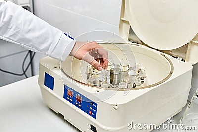 the hand of a chemical laboratory employee puts a blue drug into the experimental Stock Photo