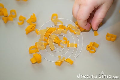 hand of child collecting letters from pasta from table. development of fine motor skills of hands. Montessori technique. Learn Stock Photo