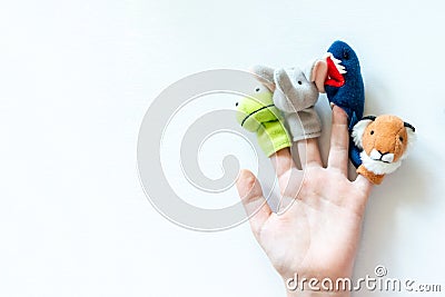 Hand of a child with finger puppets, toys, dolls close up on white background with copy space - playing puppet theatre and Stock Photo