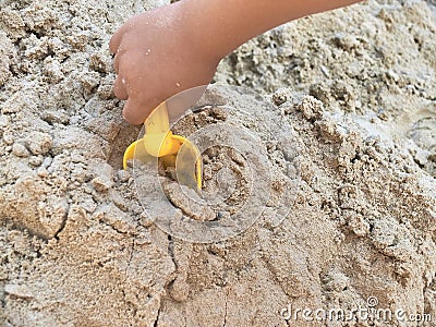 Hand of child playing in the sandbox with yellow scoop Stock Photo