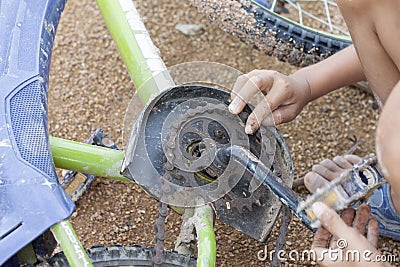 Hand of children practice repairing a chain link of a bicycle by themselves. Stock Photo