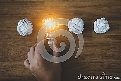 Hand choose light bulb and crumpled office paper Stock Photo