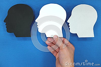 Hand choosing between multiple versions of self. Male silhouette head profile in blue background. Stock Photo