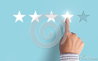 Hand choosing 4 stars on blue background - Good feedback concept Stock Photo