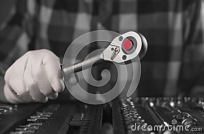 Hand close up in white glove with metal steel socket ratchet handle over toolkit with negative gray, black and white Stock Photo