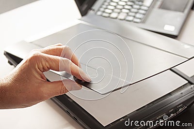 A hand closing a flatbed scanner with a laptop computer in the background. Selective focus Stock Photo