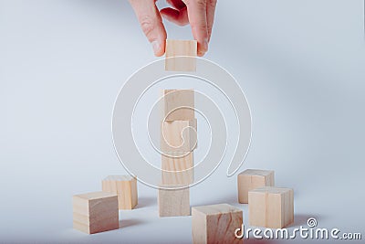 Hand completing tower made of wooden cubes Stock Photo