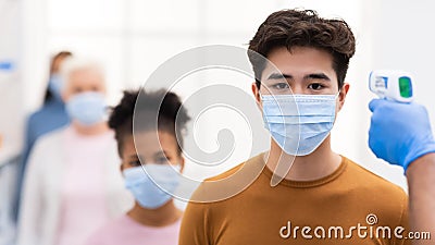 Hand With Contactless Themometer Scanning Forehead Of Chinese Man Indoors Stock Photo