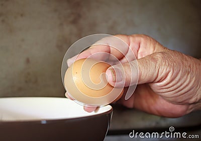 Hand Cracking and pouring Egg into a Bowl. Stock Photo
