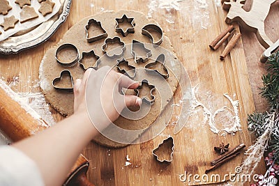 Hand cutting christmas gingerbread cookie man on dough on background of wooden rolling pin, cookies, metal cutters, christmas dec Stock Photo