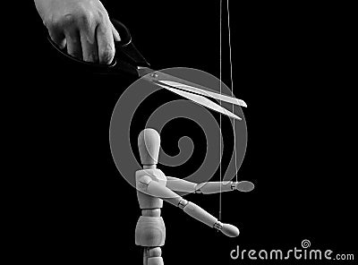 Hand cutting strings over puppet with scissors. Freedom, overcoming addiction, liberation from slavery, abuse, abusive Stock Photo