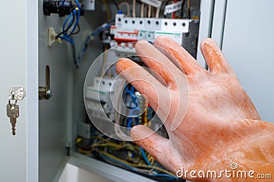 A hand in a dielectric glove opens the door to the electrical panel Stock Photo