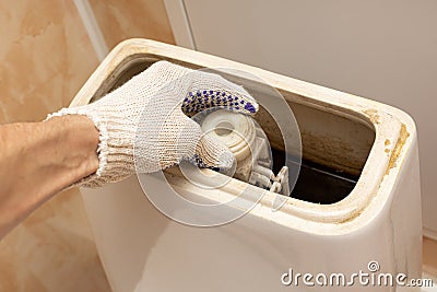 hand dismantling the flush mechanism of the toilet tank Stock Photo