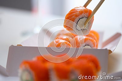 Hand with disposable chopsticks holds sake nigiri sushi with salmon fish Stock Photo