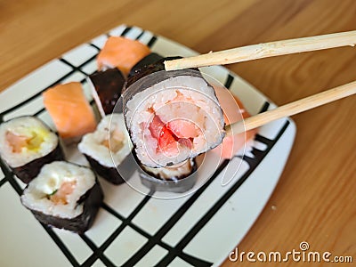 Hand with disposable chopsticks holds sake nigiri sushi with salmon Stock Photo