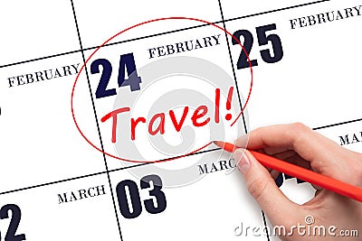 Hand drawing a red circle and writing the text TRAVEL on the calendar date 24 February. Travel planning. Stock Photo