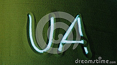 Hand drawing the Ukrainian symbols UA in the Green Sand. Stock Photo
