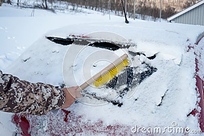 Hand driver using brush sweeping snow on windscreen car Stock Photo